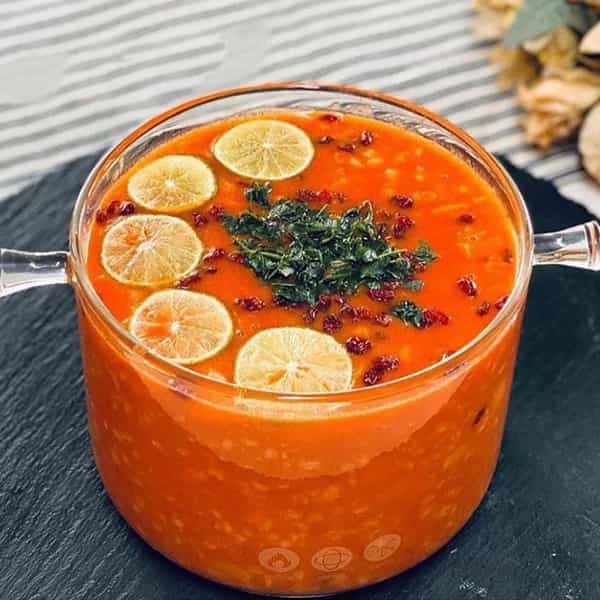 سوپ جو با تزیین زرشک، جعفری خرد شده و اسلایس لیمو.